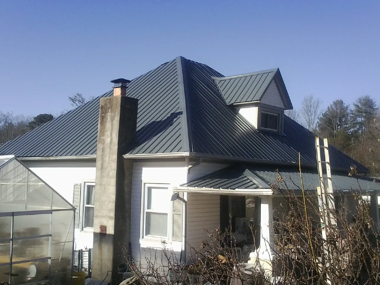Dark blue standing seam metal roof on a white farmhouse with dormer — Slate & Tile Roof Repair by Roofing Brothers in Cornwall