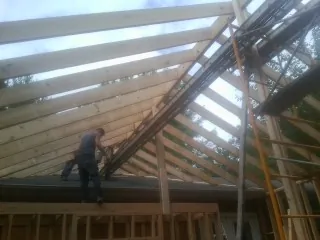 Rafters going up over a new addition with a worker on the wall in Cornwall