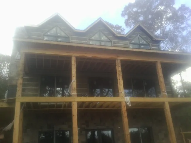 Dormers and porch framing on a large log home under construction — Roof Coating work by our crew in Cornwall