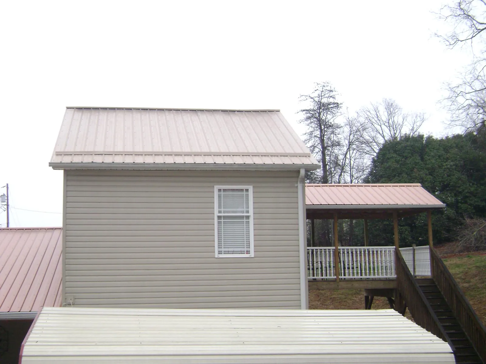 Tan metal roofs on a two story addition and attached porch, from a Roof Replacement job in Cornwall